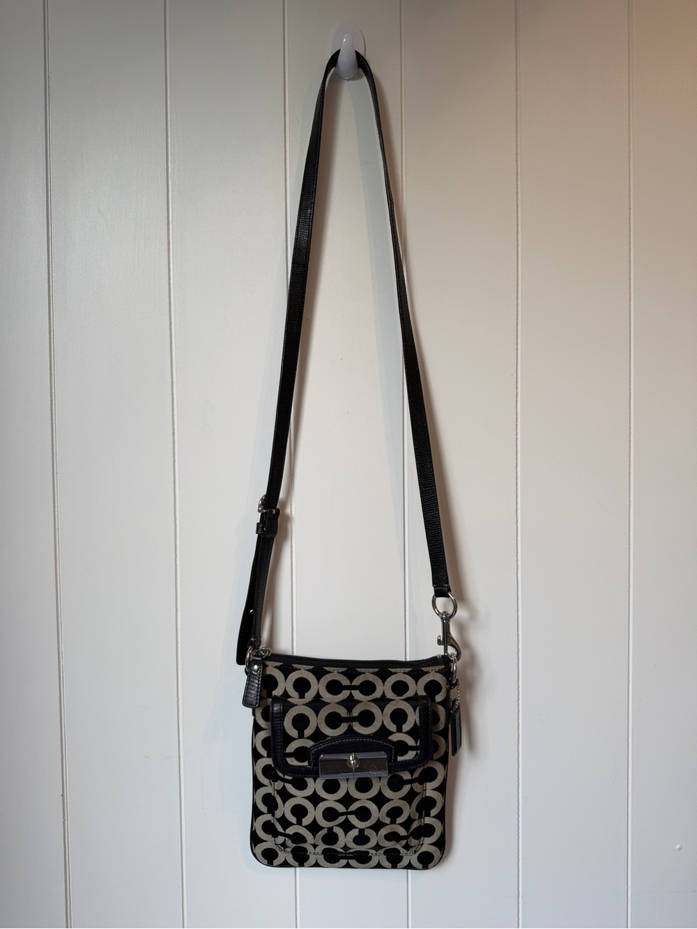 black and beige Coach signature crossbody bag with a black leather strap